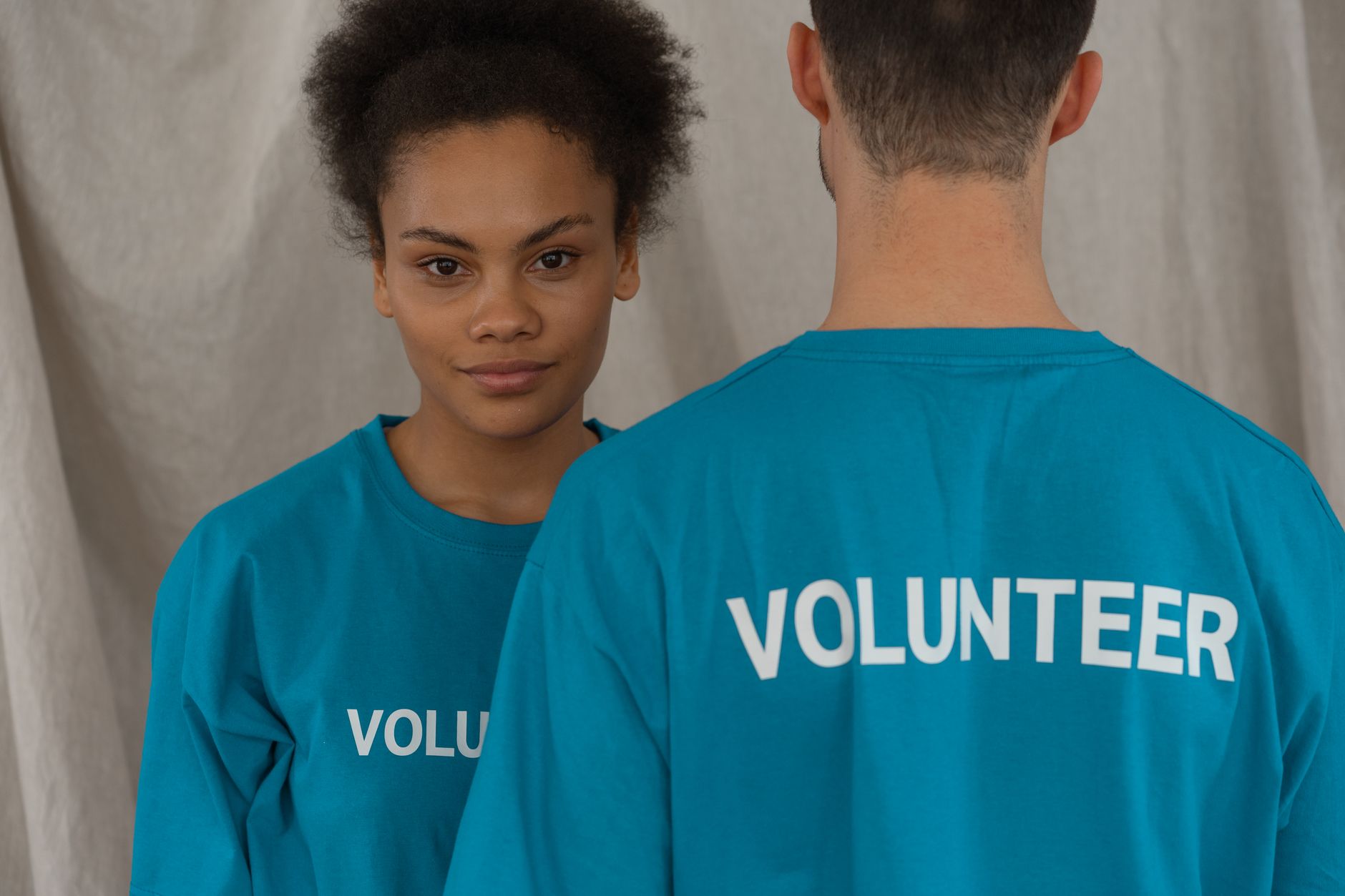Two volunteers in matching teal T-shirts printed with the word Volunteer