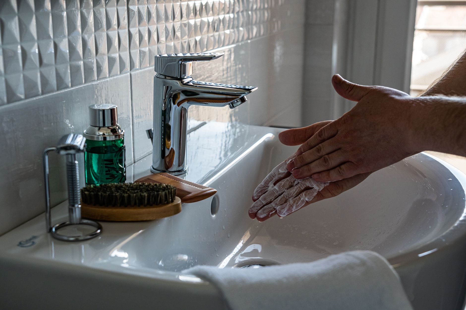 Soapy hands rinsed under a running tap at a basin