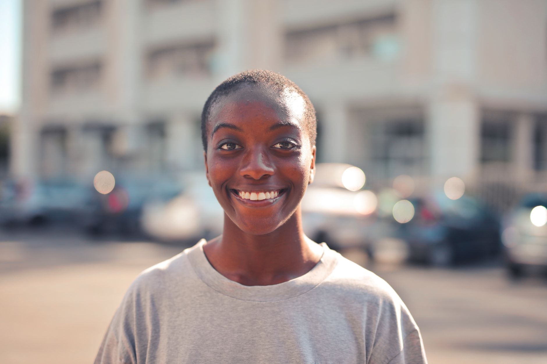 A smiling young woman with short hair on a city street